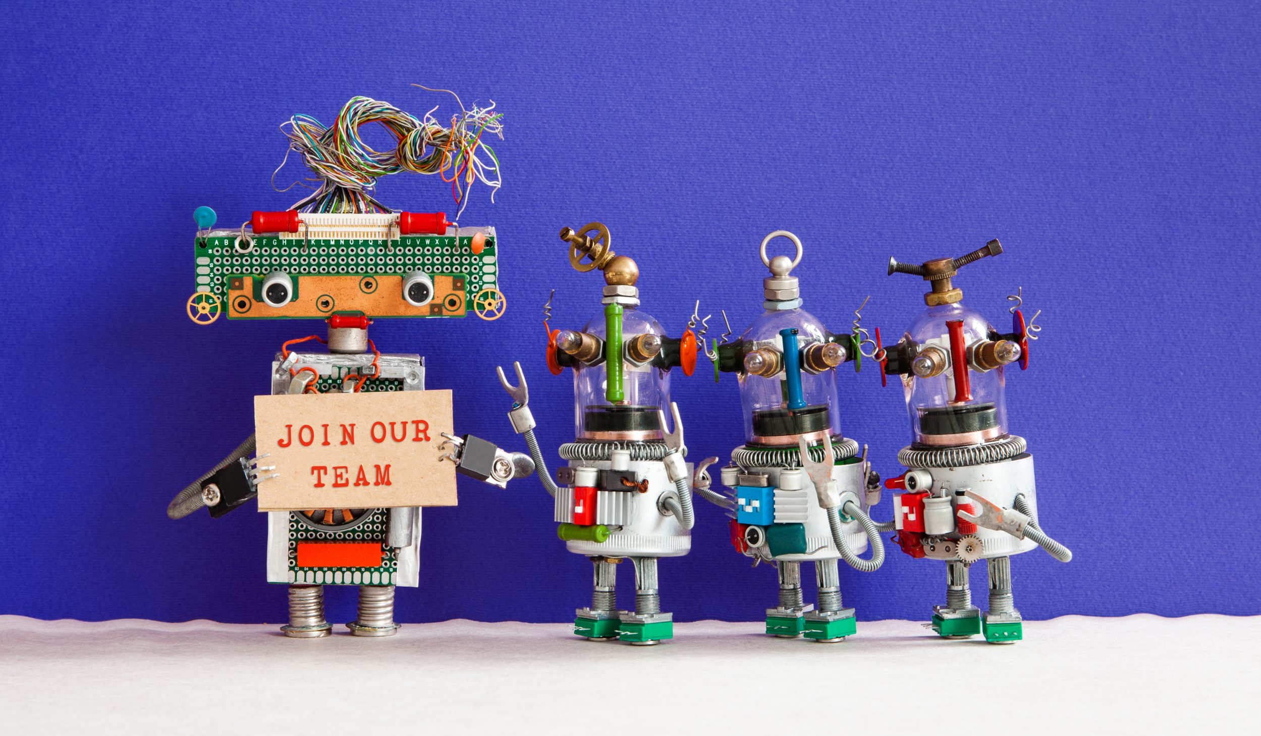 Colorful handmade robots with a Join Our Team sign